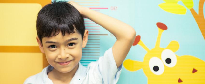 Little boy standing in front of growth chart